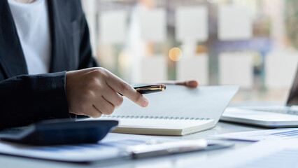 Hand pressing a calculator, analyzing financial documents while holding a pen in your finger. Young...