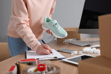 Shoes seller working at table in office, closeup. Online store