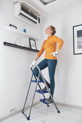 Woman cleaning aircon filters indoor unit at home.