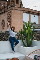 Chica guapa joven apoyada en pared blanca con iglesia de fondo en azotea de un hotel estilo soho
