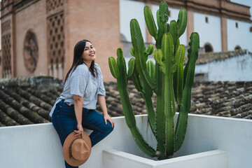 Chica guapa joven apoyada en pared blanca con iglesia de fondo en azotea de un hotel estilo soho