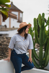 Chica guapa joven apoyada en pared blanca con iglesia de fondo en azotea de un hotel estilo soho