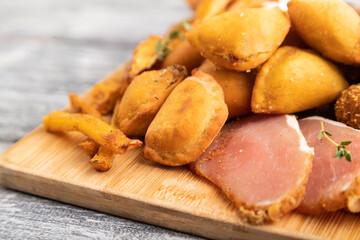 set of snacks: sausages, fried potatoes, meat balls, dumplings, basturma. Side view, selective focus.