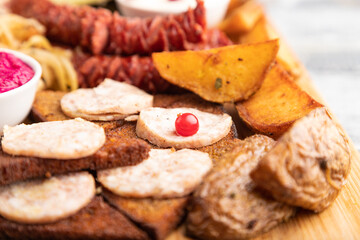 set of snacks: sausages, sauerkraut, marinated onion and cucumber, baked potato. Side view, selective focus.