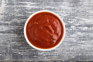 ceramic sauce bowl with, tomato sauce on a gray. Top view, copy space.