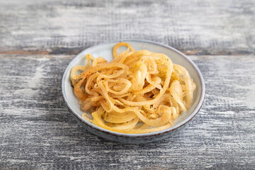 marinated onion on a gray wooden background. Side view, close up.