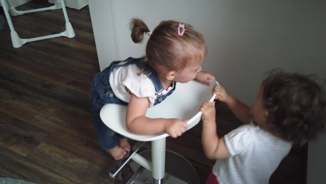 Two little girls playing with a swivel chair. Two sisters having fun at home
