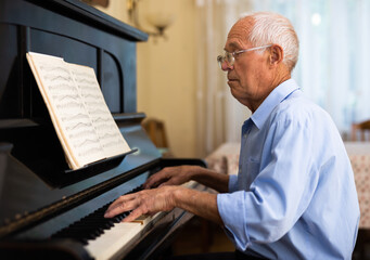 Old man playing piano at home