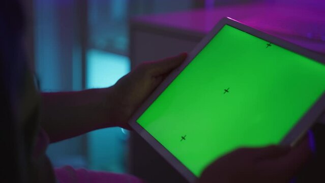 Man holding tablet pc with green screen. Room with neon lighting. High quality 4k footage