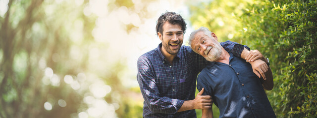 Fototapeta senior father with adult son in family concept banner background with copy space, elderly old man person are happy and enjoy with hipster son together by walking outdoor in nature obraz