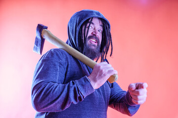 A dangerous man with a mohawk and dreadlocks covered with a hood. Menacing appearance. A middle-aged man with a beard and an unusual hairstyle holds a large ax in his hand