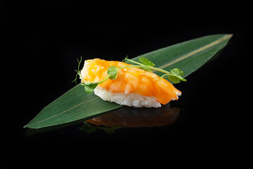 Traditional delicious fresh sushi roll set on a black background with reflection. Sushi roll with rice, nori, cream cheese, tobiko caviar, avocado. Sushi menu. Japanese kitchen. Asian food