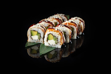 Traditional delicious fresh sushi roll set on a black background with reflection. Sushi roll with rice, nori, cream cheese, tobiko caviar, avocado. Sushi menu. Japanese kitchen. Asian food