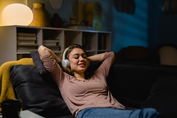 young woman relaxing at home listening music on headphones