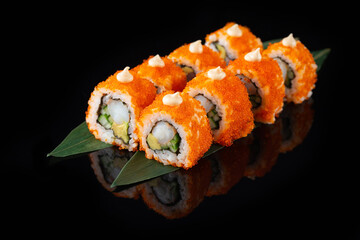 Traditional delicious fresh sushi roll set on a black background with reflection. Sushi roll with rice, nori, cream cheese, tobiko caviar, avocado. Sushi menu. Japanese kitchen. Asian food