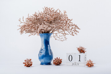 wooden calendar and a vase of flowers in the office. July 1