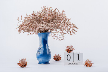 wooden calendar and a vase of flowers in the office. August 1