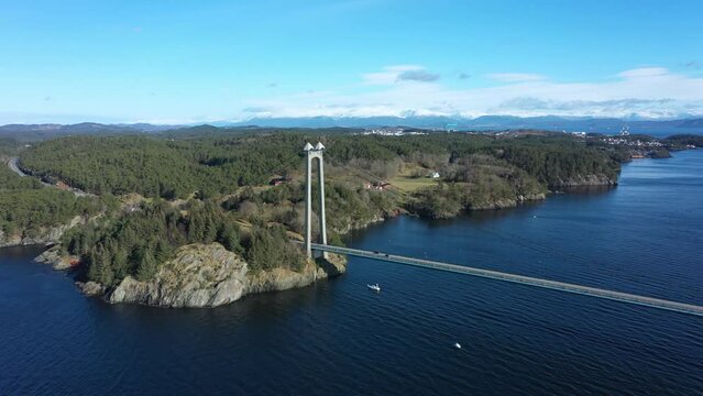 Stord bridge triangle connection on Stord island in Norway - Bridge with traffic in beautiful sunny day - Aerial flying over sea and looking towards island of Stord