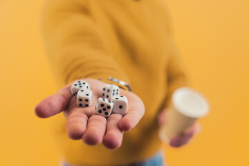 Five dice lying on a hand of a caucasian person. Studio shot over yellow background. High quality...