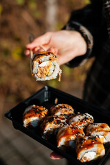 Girl takes sushi with chopsticks from a takeaway box. © Евгений Гвоздев