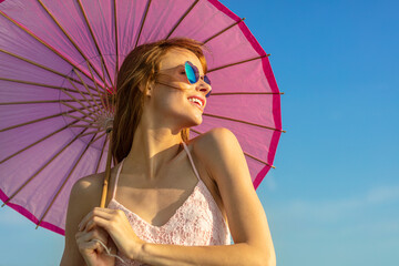Smiling Boho chic carrying parasol on beach vacation © Spotmatik