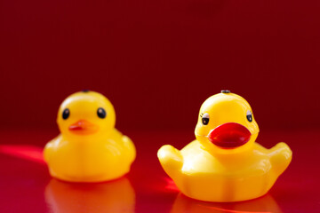 Yellow rubber duck with big lips on a red background. Natural beauty. Artificial made lips. Botox lips. Duck lips.