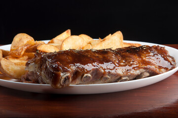 pork ribs with barbecue sauce and rustic potatoes isolated on white background close up