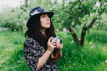 hipster girl with vintage camera photographs nature in a garden