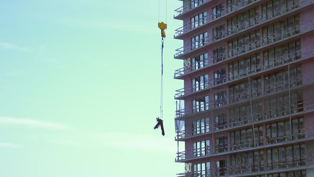 Raise building load to height. Crane lowers loads at construction site. Work process. Crane lifts materials on roof for construction decoration. raised telescopic boom on site. sling hoist crane arm