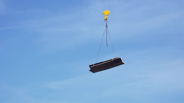 Raise building load to height. Crane lowers loads at construction site. Work process. Crane lifts materials on roof for construction decoration. raised telescopic boom on site. sling hoist crane arm