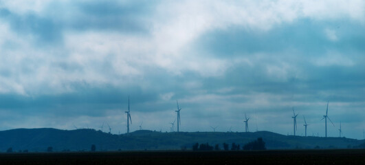 Windmill power on top of a hill with cloudy weather