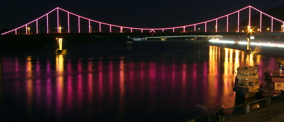 Park pedestrian bridge over the Dnieper River in the capital of Ukraine - Kyiv at night with beautiful backlight