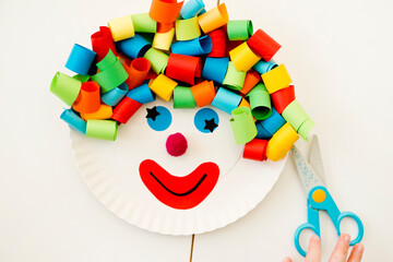 Paper plate clown. DIY games at home, activities for pre-school Kids. 5 minute crafts. Children joy and funny to cut a hair for clown. Red Nose Day theme.