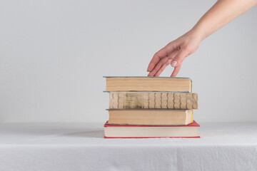 Stack of old rustic vintage books with the hand on white table 