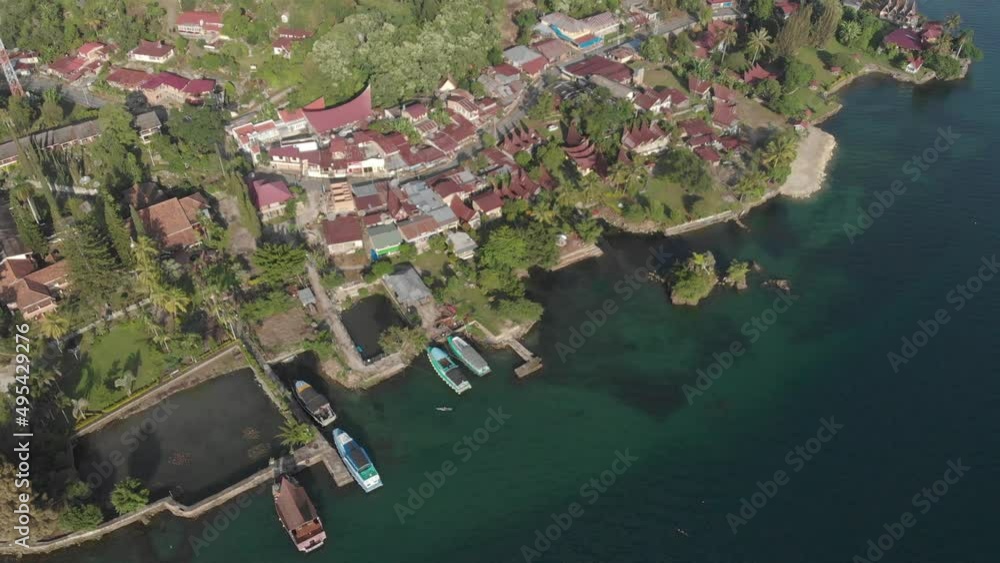 Wall mural Aerial: flying over lake Toba and Samosir Island Sumatra Indonesia. Tuk Tuk traditional village and tourist destination. Huge volcanic caldera water ecosystem, lush green equatorial forest.