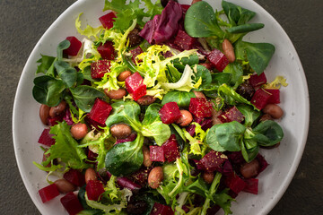 Warm salad with mixed salad with boiled beetroot and beans with spices, top view