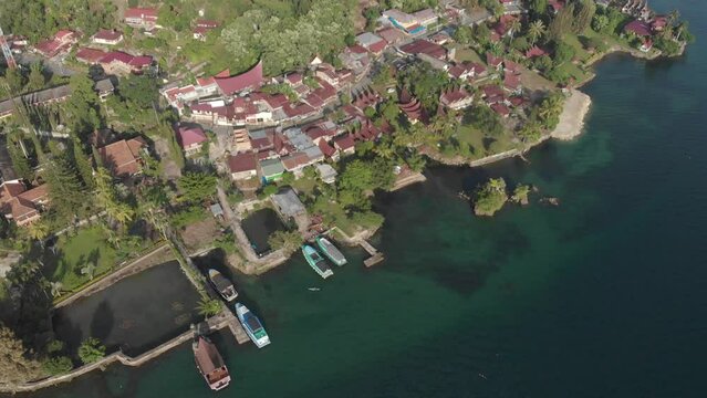 Aerial: flying over lake Toba and Samosir Island Sumatra Indonesia. Tuk Tuk traditional village and tourist destination. Huge volcanic caldera water ecosystem, lush green equatorial forest.