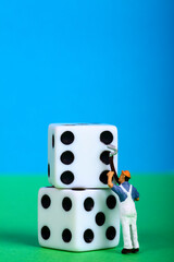 Conceptual image of miniature figure painting the spots on dice, change of luck concept
