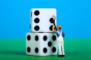 Conceptual image of miniature figure painting the spots on dice, change of luck concept