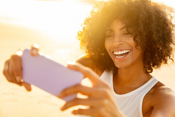 African American woman taking fun selfies on beach