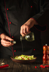 Preparation of salad from viburnum and cabbage. The chef adds oil to a fresh vegetable salad. Vegetarian cuisine