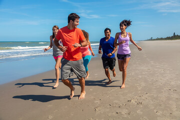 Happy young friends jogging together at beach resort