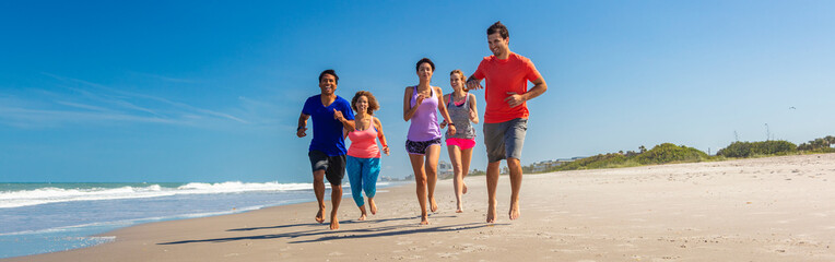 Panoramic view of friends jogging together on beach