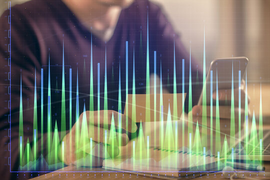 Double exposure of man's hands holding and using a phone and financial graph drawing. Analysis concept.