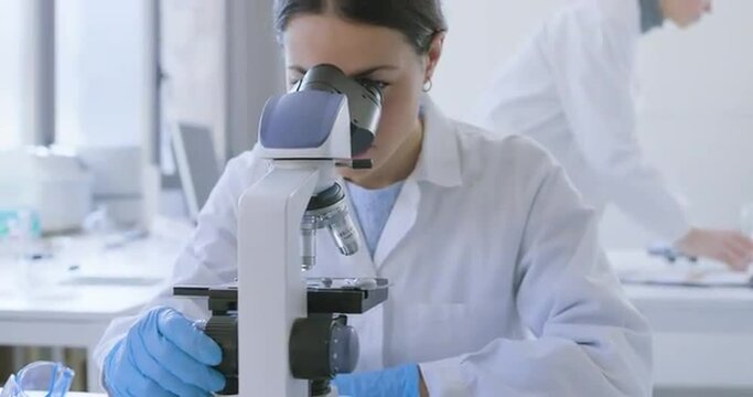 Researcher using a microscope in the clinical lab