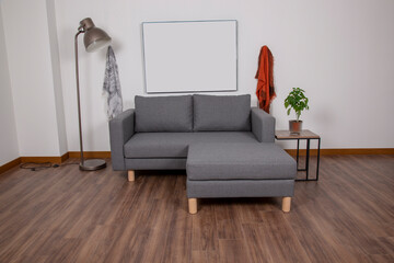 Gray living room with sofa. Poster on wooden cabinet with plant near gray sofa in simple living room interior. real photo