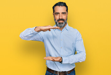 Middle aged man with beard wearing business shirt gesturing with hands showing big and large size...