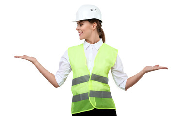 Smiling young female engineer in a white safety helmet and a green reflective vest holds in her hands an invisible product advertisement on a white isolated background