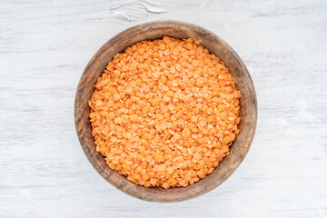 Orange or red lentils in wooden bowl on white background.