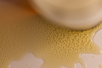 
Beer in a glass spilled at the base of the glass. Macro view.